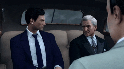 a man in a suit and tie talks to another man in a car