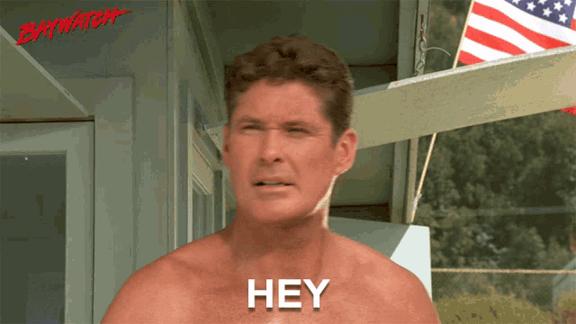 a shirtless man says hey in front of a baywatch logo