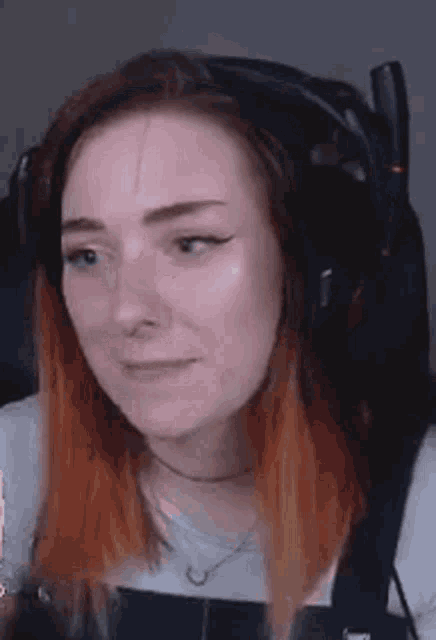 a woman is wearing headphones and making a funny face .