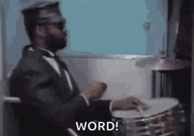 a man in a suit and tie is playing drums in a room .