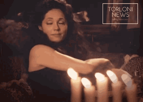 a woman is surrounded by lit candles and a torloni news advertisement