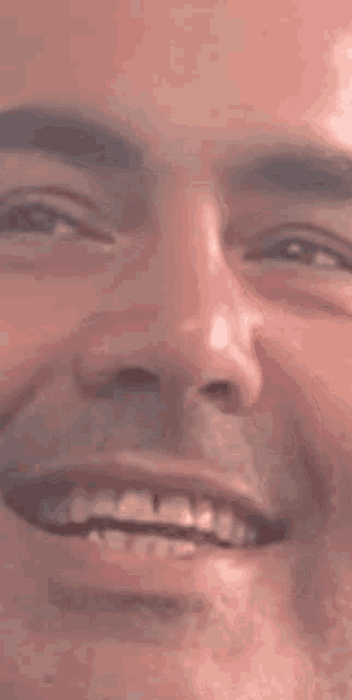 a close up of a man 's face smiling and looking at the camera .