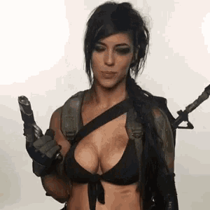the woman is wearing a bikini and holding a gun .