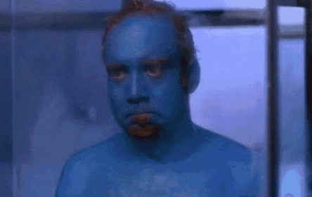 a man with his face painted blue is looking at the camera with his mouth open .