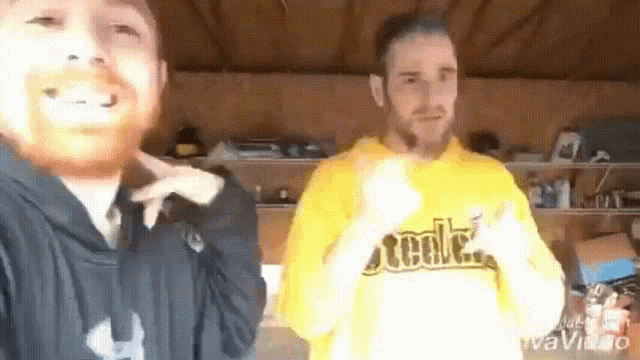 two men are standing next to each other and one of them is wearing a yellow steelers shirt