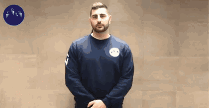 a man wearing a blue sweater with a white logo on the front
