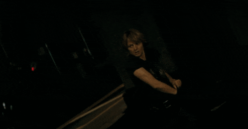 a man is smoking a cigarette in a dark room with a blurry background .