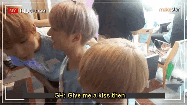 a group of young men are standing next to each other and one of them is saying " gh : give me a kiss then " .