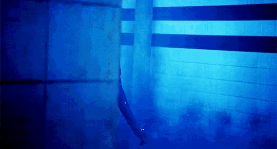 a person is standing in a dark room with a blue light shining on them