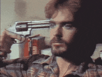 a man in a plaid shirt is holding a gun to his forehead