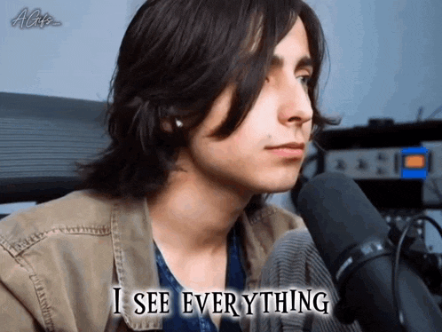 a young man sitting in front of a microphone with the words " i see everything " above him