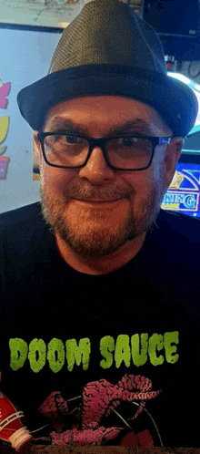 a man wearing glasses and a hat is wearing a doom sauce shirt
