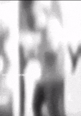 a blurry picture of a person standing next to a pole in a black and white photo .