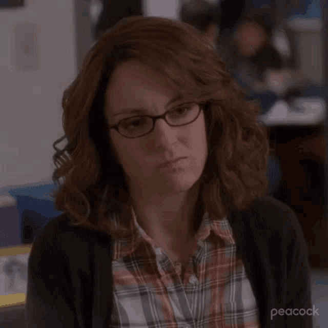 a close up of a woman wearing glasses and a plaid shirt .