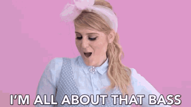 a woman is wearing a pink headband and a blue shirt and says `` i 'm all about that bass ''