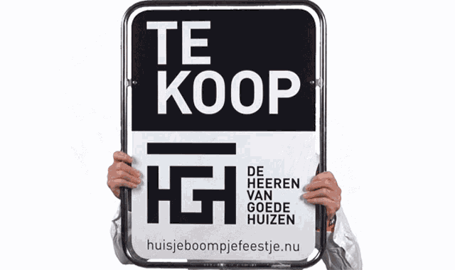 a man holds up a sign that says te koop de heeren van goede huizen