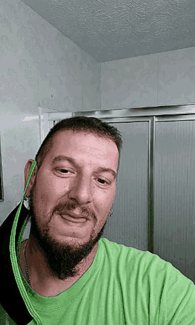a man with a beard wearing a green shirt looks at the camera