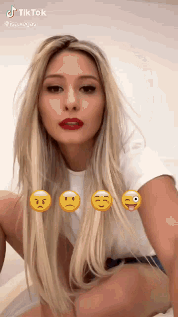 a woman wearing a white shirt and shorts is kneeling down with emojis on her face .