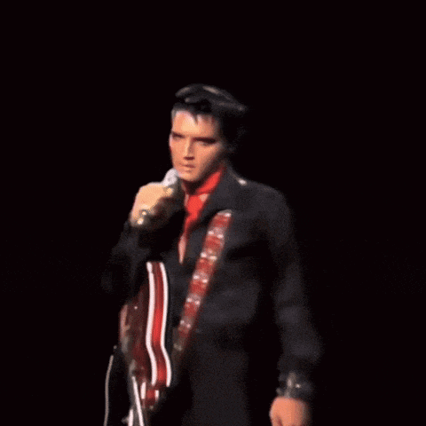 a man singing into a microphone in front of a wall of silhouettes of people
