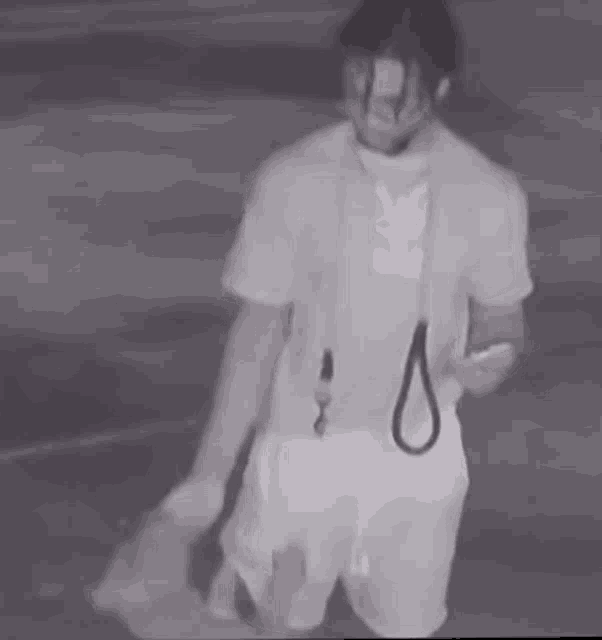 a man in a white shirt and shorts is holding a dog on a leash .