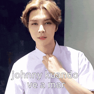a young man in a white shirt is adjusting his tie with the words johnny kuando ve a mar below him
