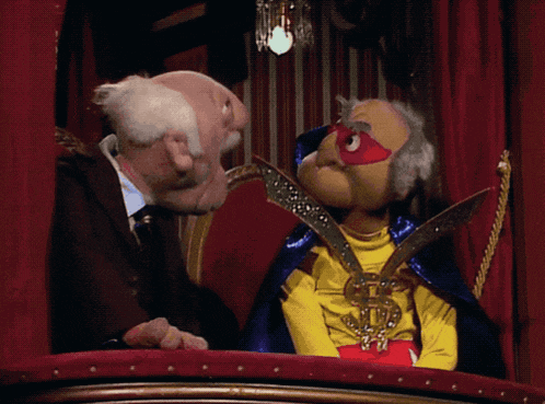 a puppet in a superhero costume talks to an older man