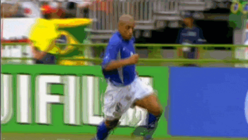 a soccer player is running in front of a banner that says fuji