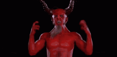 a close up of a red demon with horns looking up at the camera .