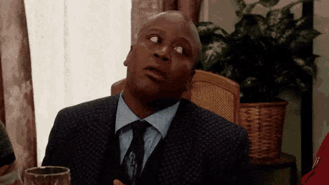 a man in a suit and tie is looking up at something while sitting at a table .