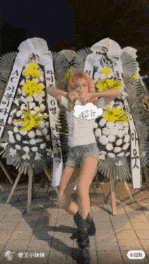 a woman with pink hair is standing in front of a bunch of wreaths that say ac