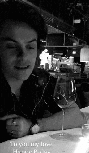 a man is sitting at a table with a glass of wine and the words " to you my love happy b-day "