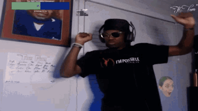 a man wearing a black i 'm possible shirt stands in front of a white board