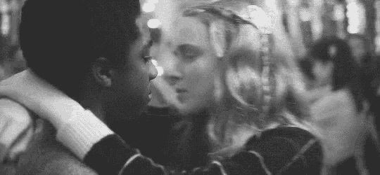 a black and white photo of a man and a woman kissing .