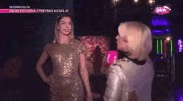 a woman is talking to a mannequin wearing a gold sequined dress
