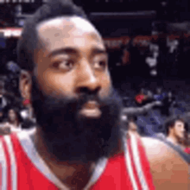 a basketball player with a beard is wearing a red and white jersey .