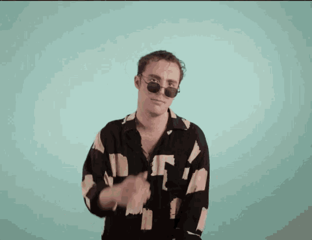 a man wearing sunglasses and a black and white shirt is dancing .