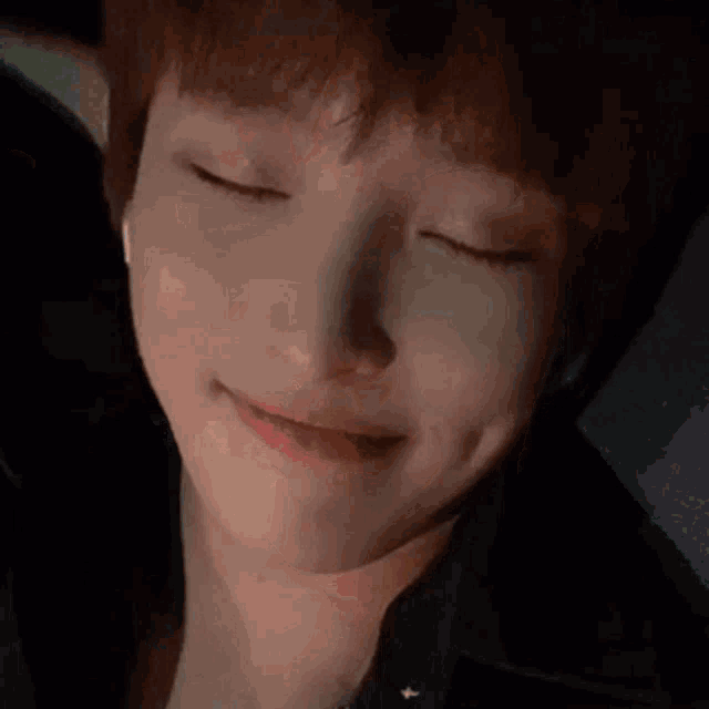a close up of a person 's face with their eyes closed and a slight smile on their face .