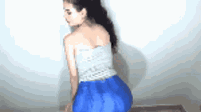 a woman is wearing a blue skirt and a gray top .