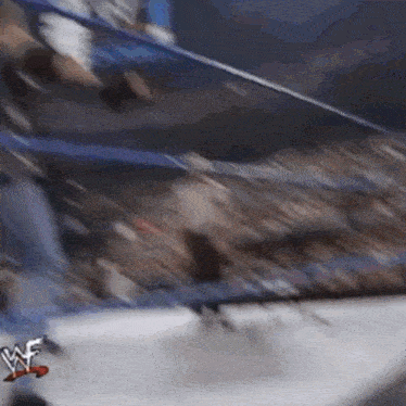 a blurry picture of a wrestler in a wrestling ring with a wwe logo on the bottom right corner .