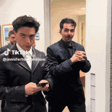 two men in suits standing next to each other with a tiktok watermark on the bottom