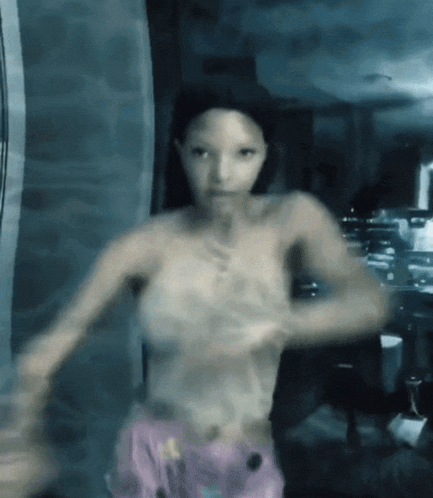 a woman without a shirt is dancing in a room