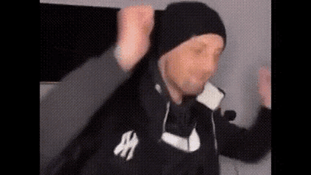a man wearing a beanie and a hoodie is dancing .
