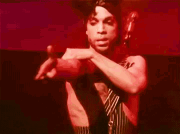 a man without a shirt and tie is holding a red object in his hand .