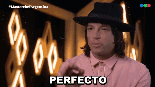 a man in a hat says perfecto in front of a neon sign