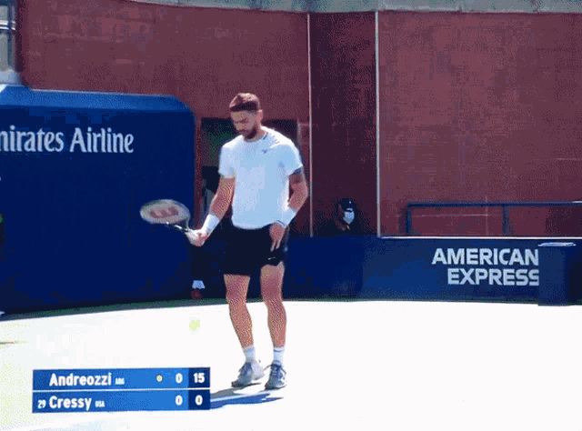 a tennis player holds a tennis racquet in front of a sign that says american express