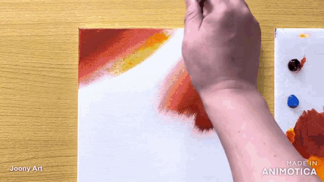a person is painting on a canvas with red and yellow paint