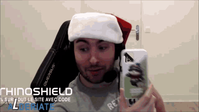 a man wearing a santa hat and headphones holds a cell phone