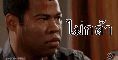 a man is sweating profusely and looking at the camera with a foreign language written on his face .