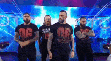 a group of men are standing on a stage in front of a blue background .