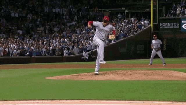 a pitcher wearing a jersey that says cincinnati reds throws a pitch
